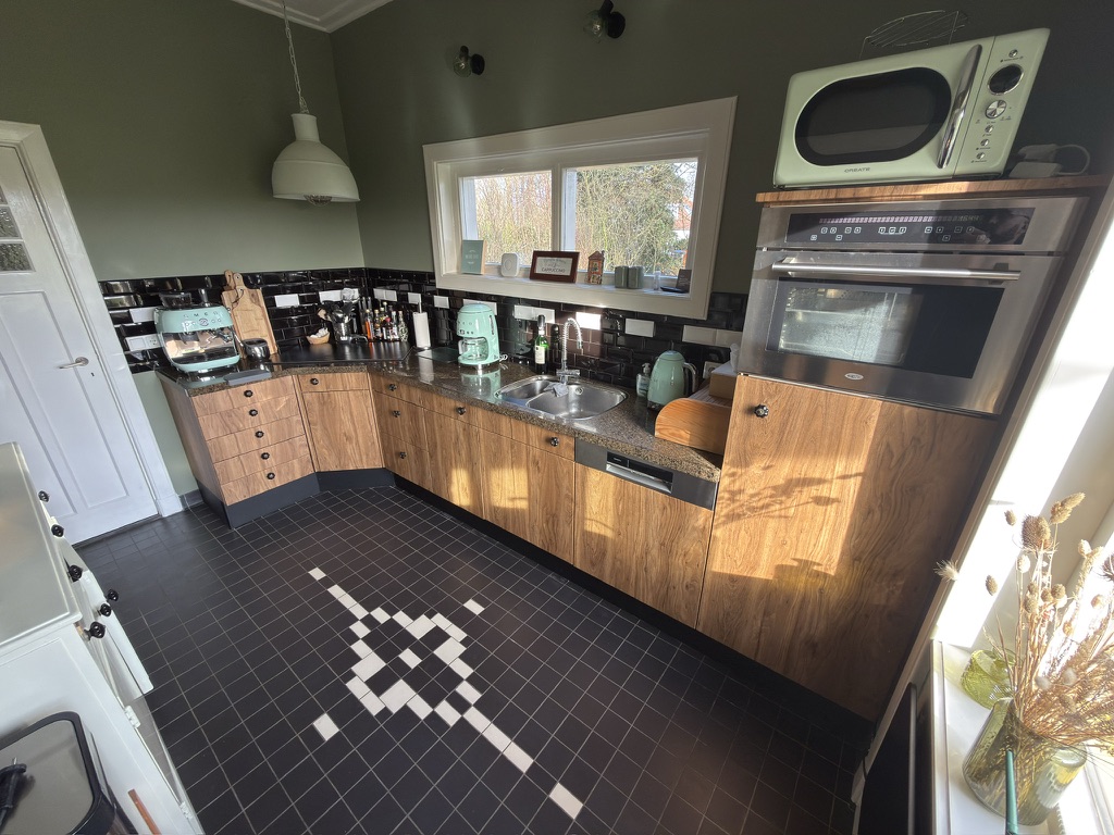 Keuken na restyling met warme houtlookfronten, zwarte tegels en bestaande werkbladen